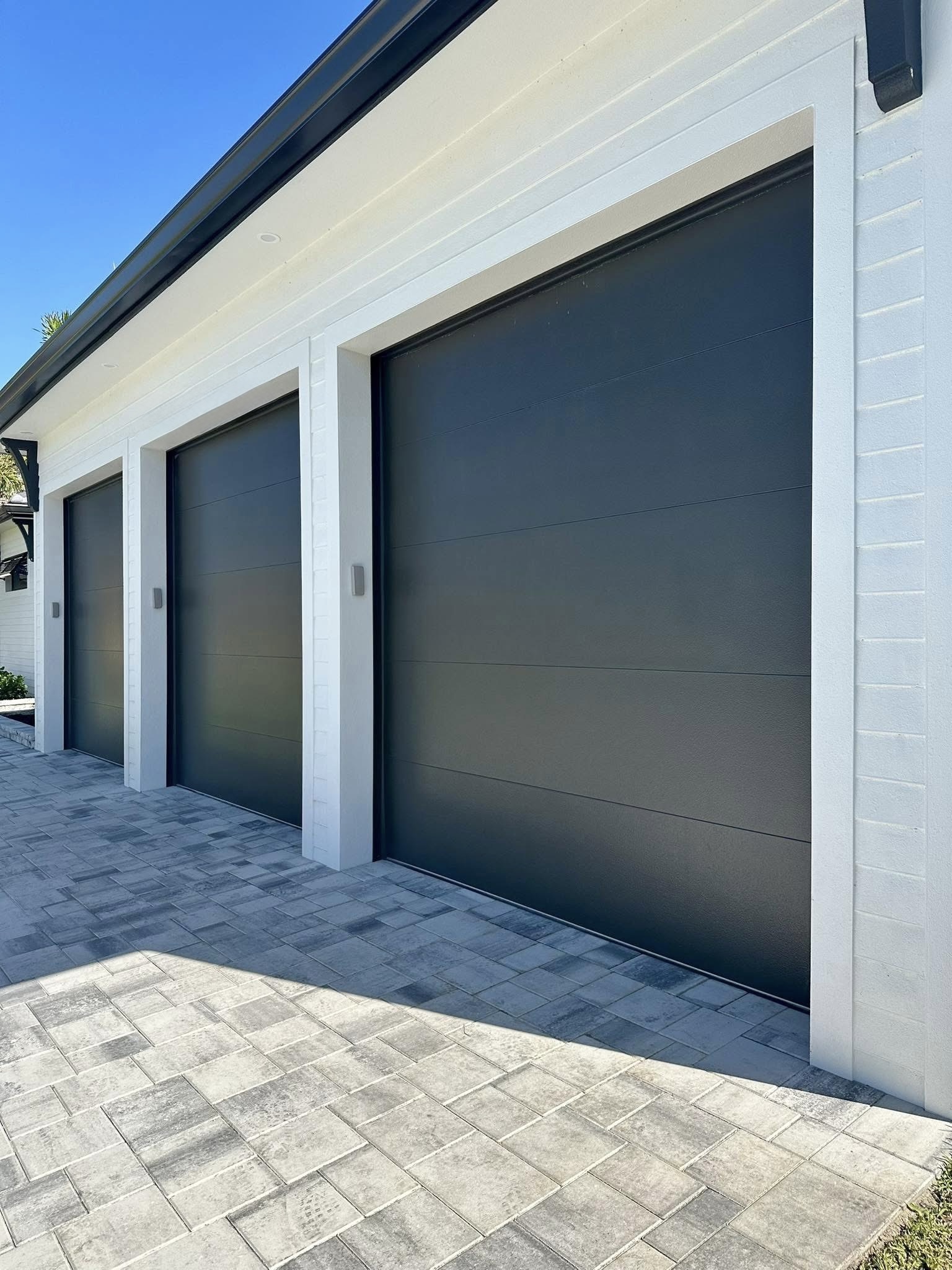 Flush steel garage door in dark grey on modern white home — Metro Vancouver