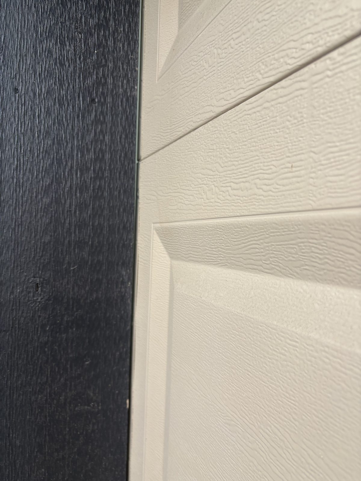 Worn or missing garage door weather seal showing gap at door panel corner