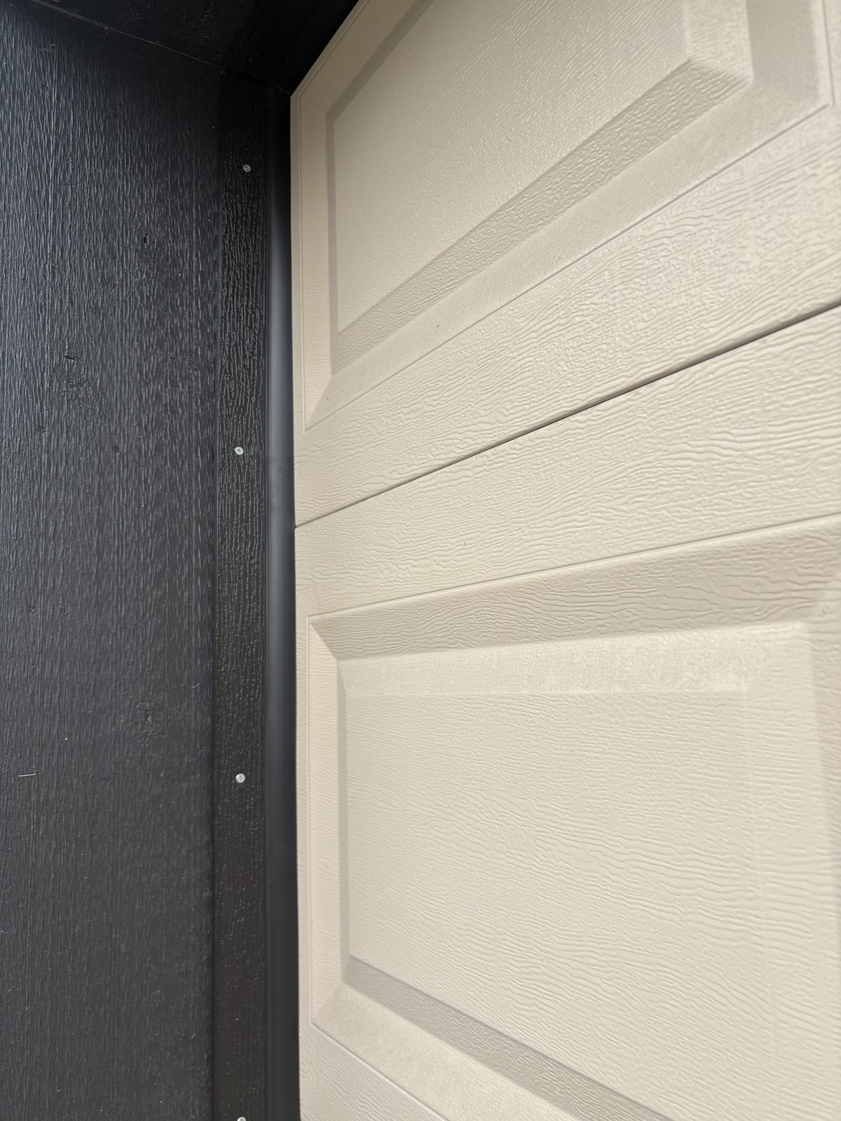 New vinyl weather stop installed on garage door frame — finished result showing seal against cream door panel
